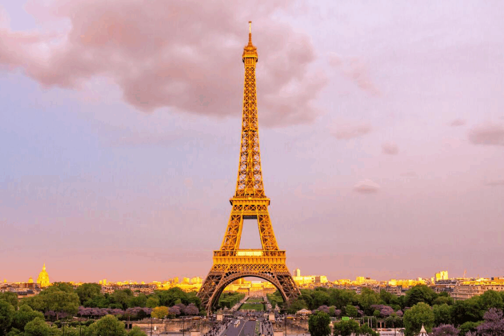 Menara Eiffel di Paris saat senja dengan langit berwarna pastel, mewakili keindahan budaya Prancis dan pentingnya memahami bahasa lokal untuk berinteraksi dengan warga setempat.